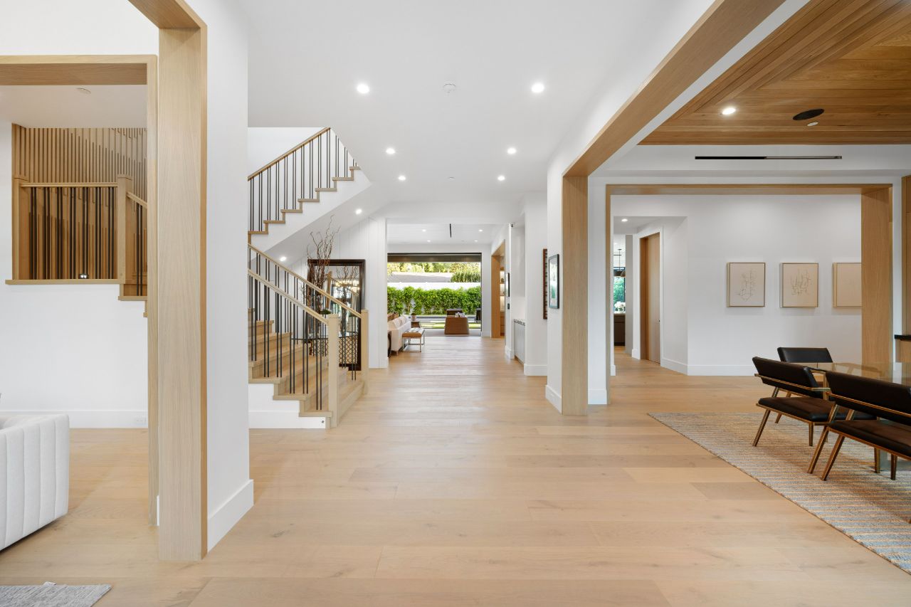 Long apartment hallway with a plank wood floor running toward a window.