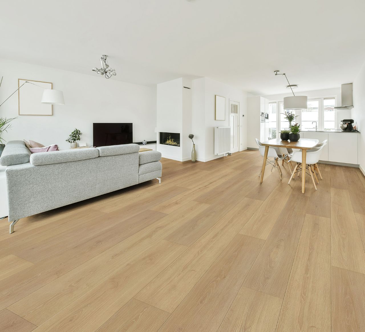 Wood flooring connecting an open-plan living room, dining area and kitchen.