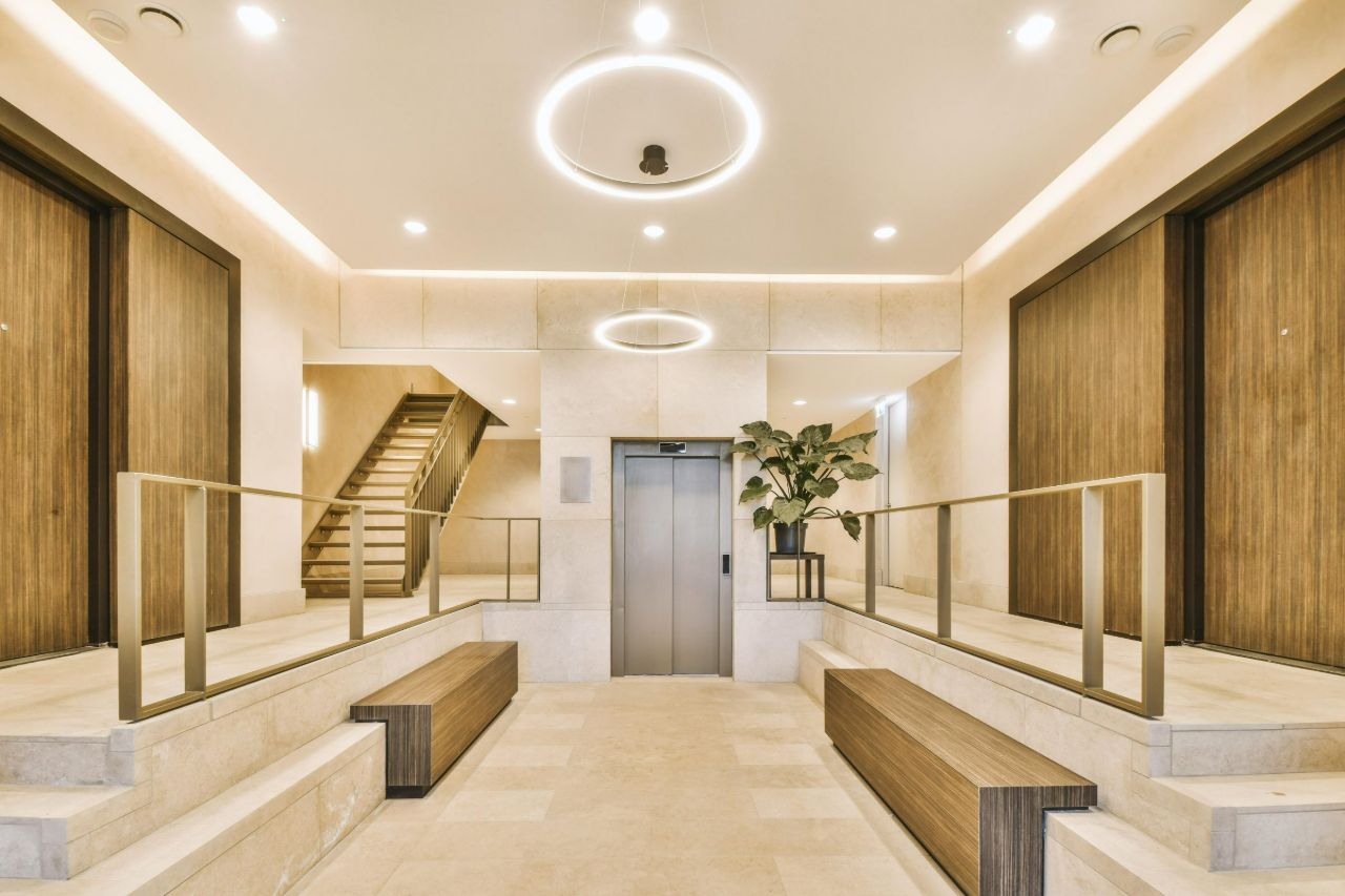 Contemporary building lobby with an elevator, benches and a light-toned floor.